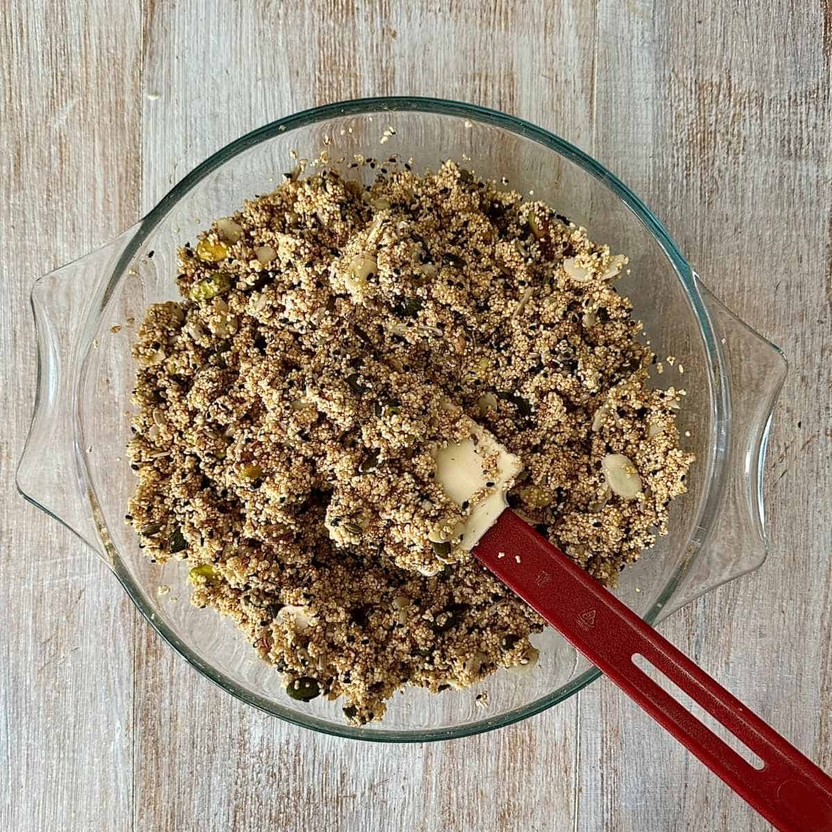 A large glass bowl containing sugar free granola ingredients mixed together with apple juice.