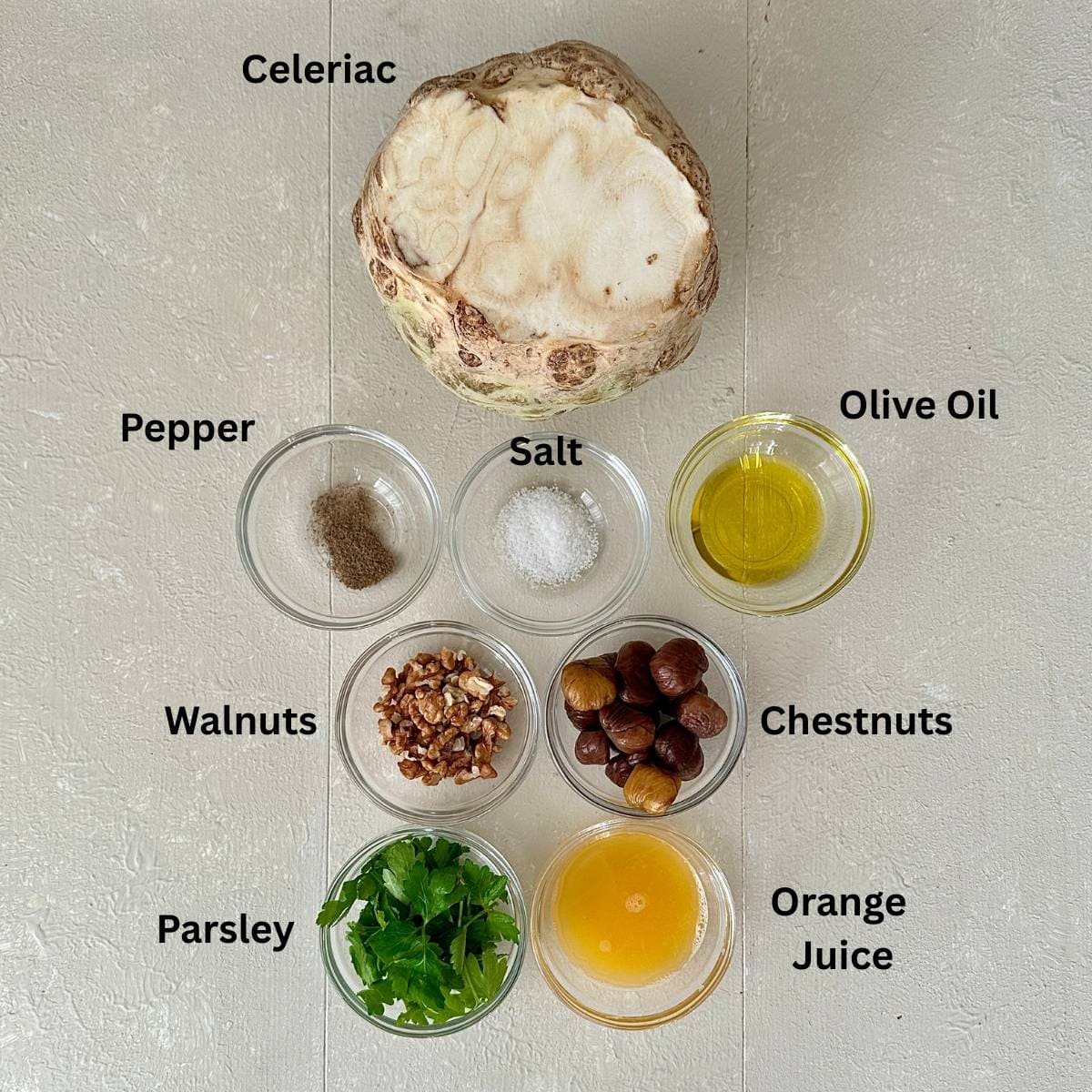 Ingredients for roasted celeriac, Carppaccio-style with an orange, walnut and chestnut dressing. Displayed install glass dishes.