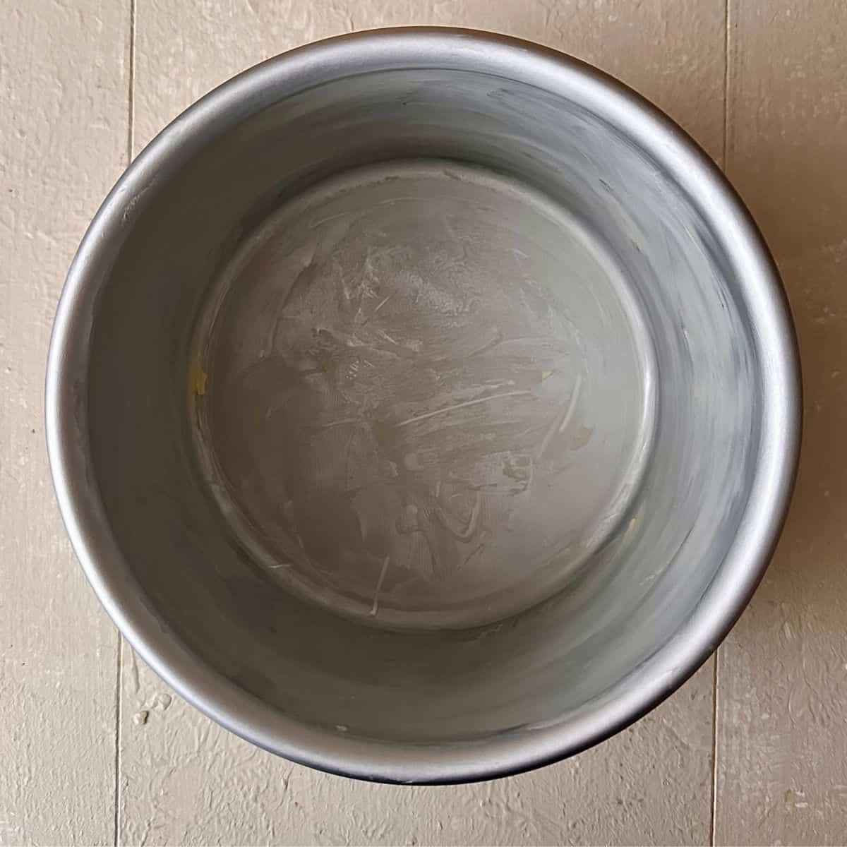 Metal six inch cake tin coated on the inside with butter for making dark chocolate mud cake.