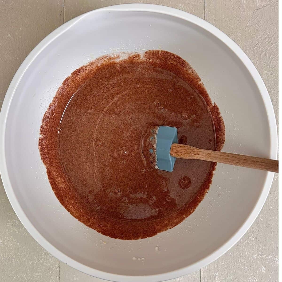 Cake mix for a dark chocolate mud cake in a bowl. Melted dark chocolate and butter mixed with beaten egg and sugar. A spatula sits in the mixture.