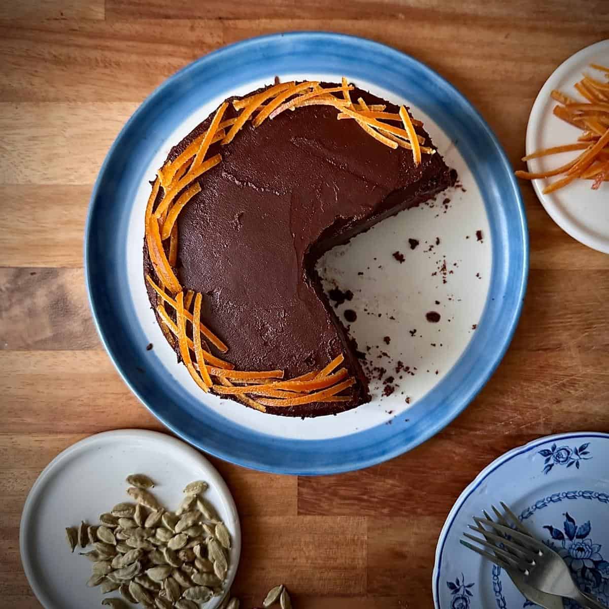 Dark chocolate mud cake with ganache on a blue-rim plate, single layer 6-inch cake with a slice removed.