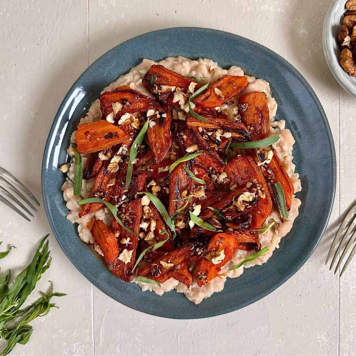 Gochujang roasted carrots served over creamy white beans, finished with chilli oil and herbs