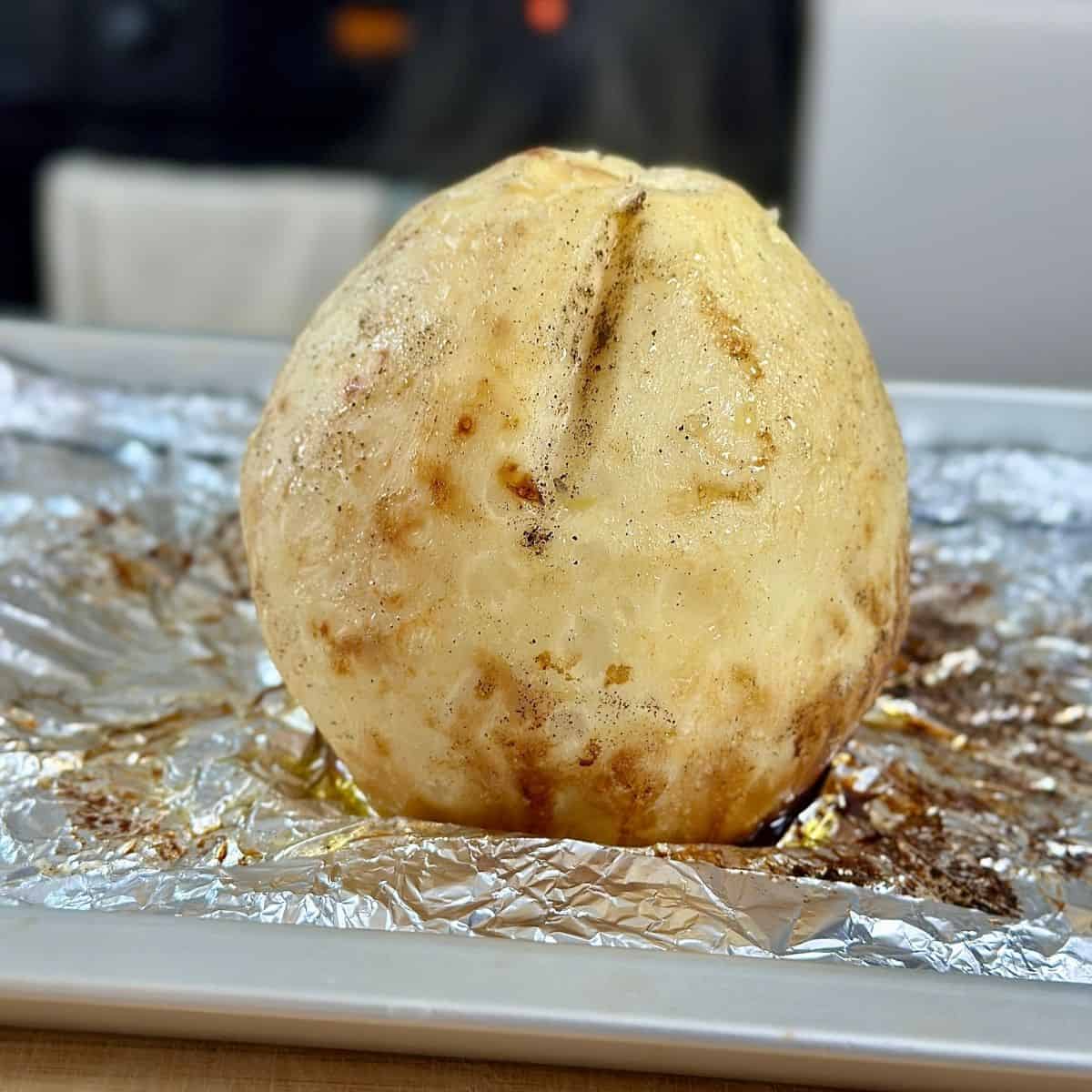 Roasted celeriac after baking in the oven, sitting on tin foil on a baking tray.