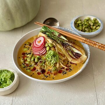 Vegetarian veggie ramen in a rich pumpkin and miso broth with noodles and greens.