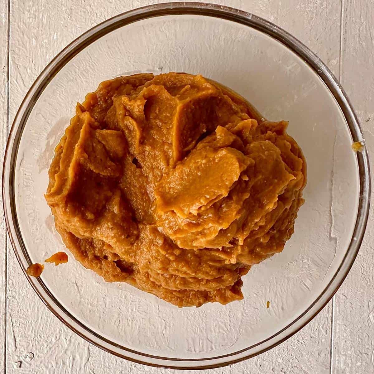 A glass bowl containing pureed pumpkin ramen broth base for veggie ramen recipe.