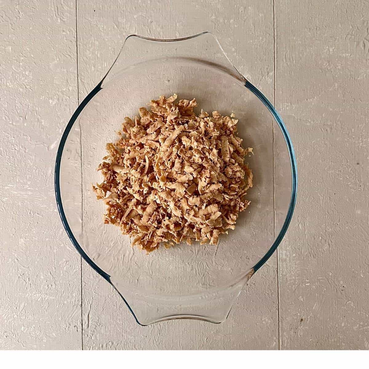 A glass bowl containing grated tempeh.
