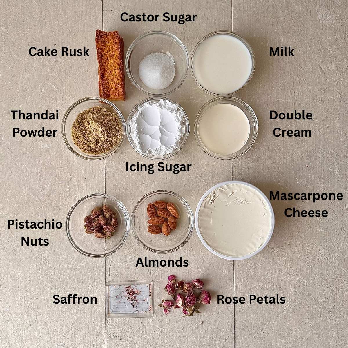 Ingredients for a no-bake thandai cream cake in small glass dishes. The ingredients are in small glass dishes.