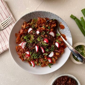Overhead kimchi white bean stew with tempeh crumble in a beige bowl.