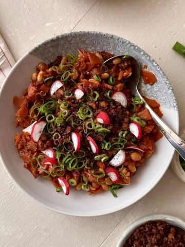 Overhead kimchi white bean stew with tempeh crumble in a beige bowl.