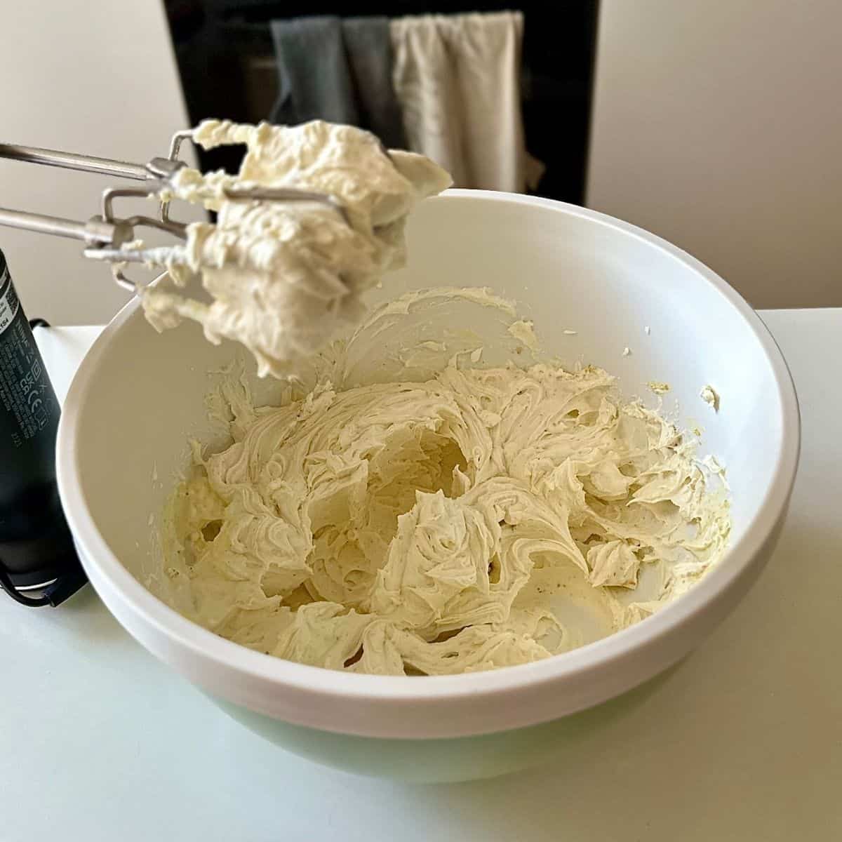 A bowl containing cream filling made with mascarpone cheese, double cream and icing sugar and thundai powder, for no bake thundai cream cake.