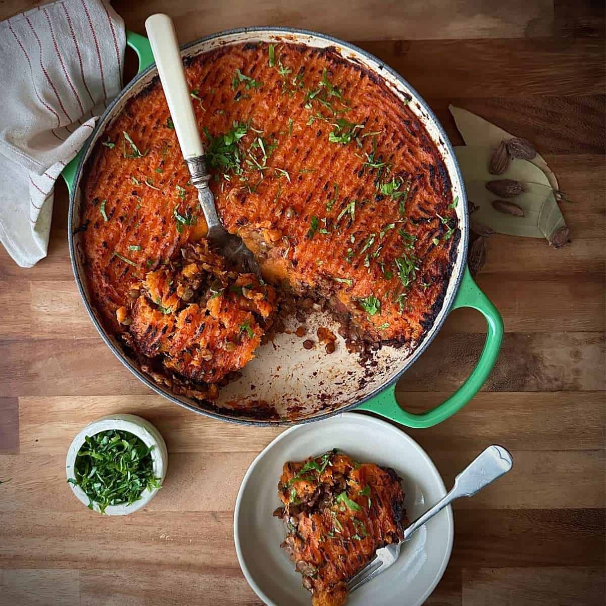 Sweet potato lentil shepherd’s pie with chestnuts and warming masala spices in a green casserole dish.