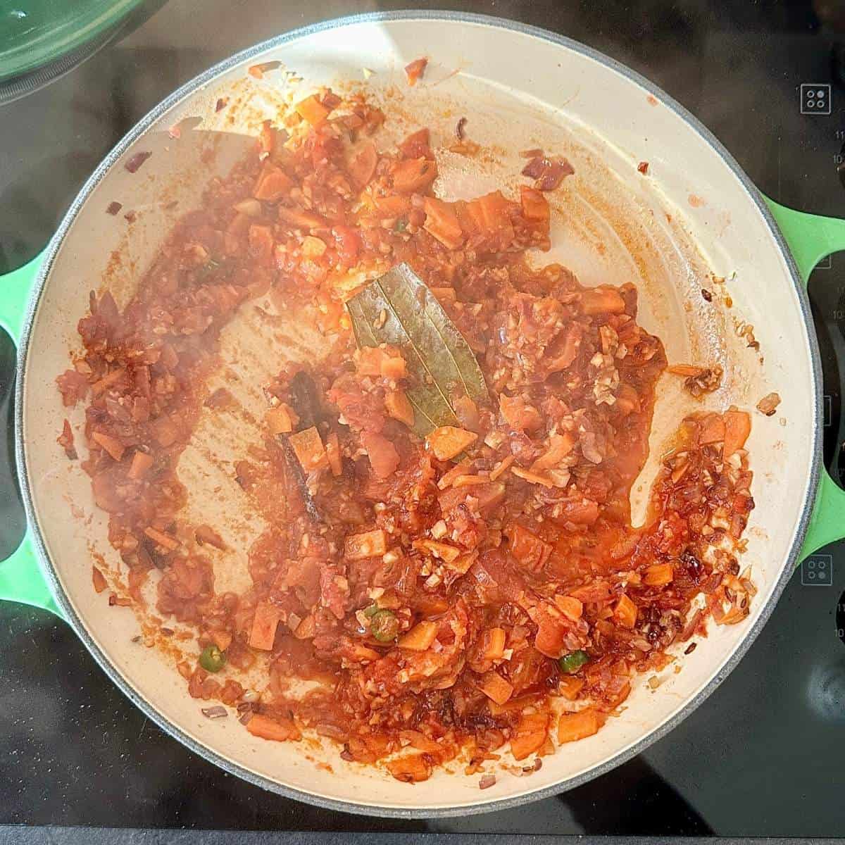 Carrots, onions, garlic, ginger, tomatoes and spices sautΓ©ing in a pan to make the lentil shepherd's pie filling.
