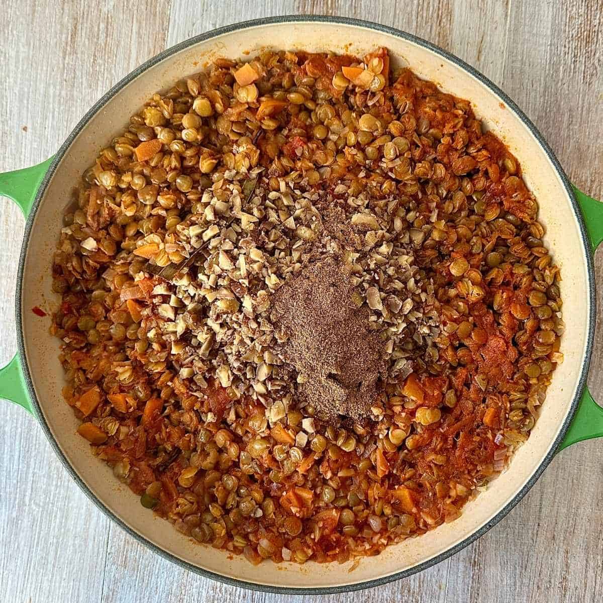 Finely chopped chestnuts and garam masala added to green lentils simmering in spiced tomato sauce for the shepherd's pie filling. Ion a large green casserole dish.