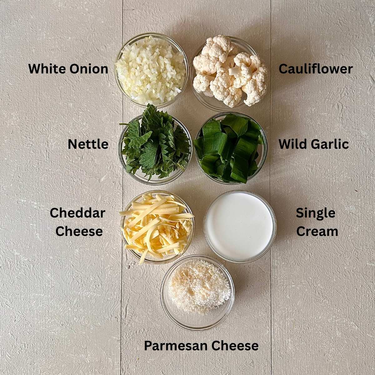Prepared ingredients for wild garlic cauliflower cheese in small glass dishes. The ingredients are annotated.