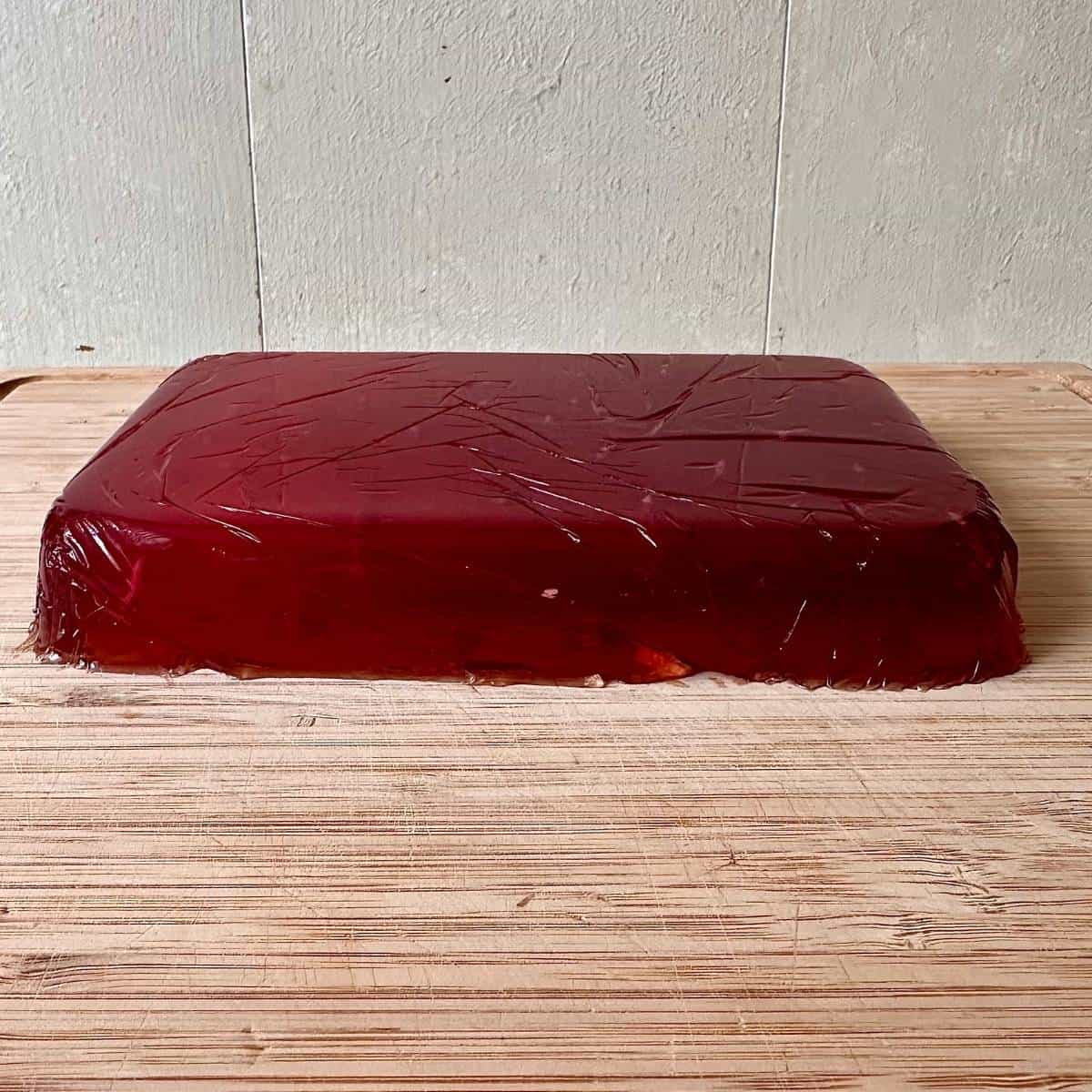 A slab of fully set flowering current jelly turned out onto a chopping board, ready to cut into squares.