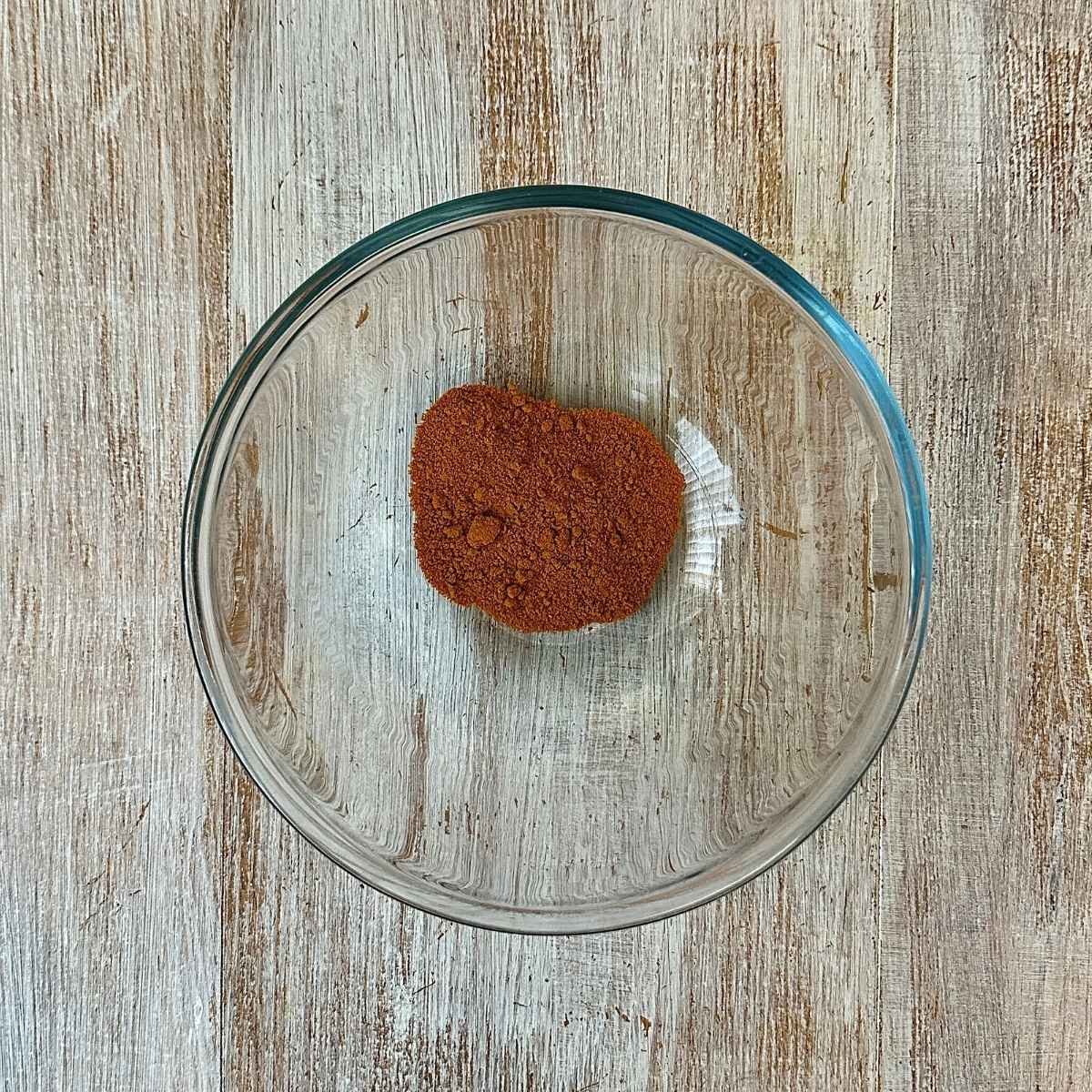 A glass bowl containing turmeric for super seed mix recipe.