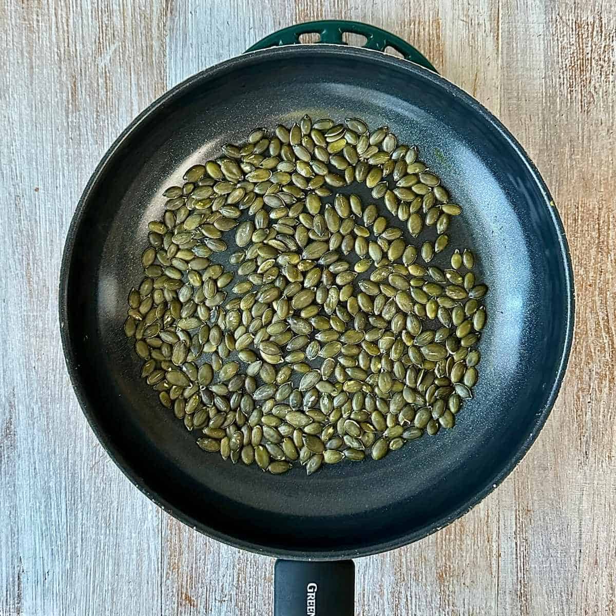 A frying pan containing pumpkin seeds ready to toast for super seed mix recipe.