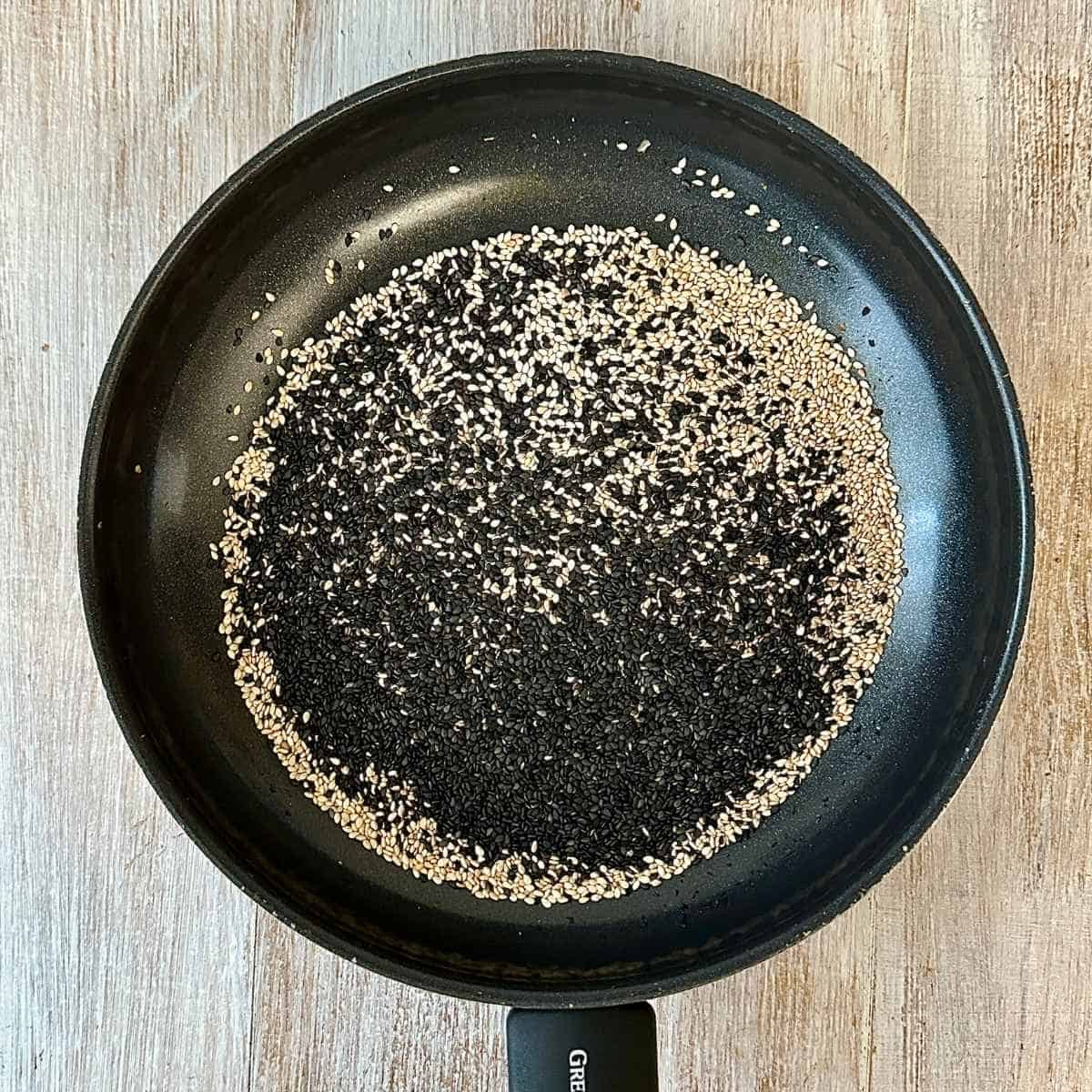 A frying pan containing black and white sesame, ready to toast, for super seed mix recipe.