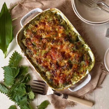 Wild garlic cauliflower cheese with nettles baked until golden in a ceramic dish.