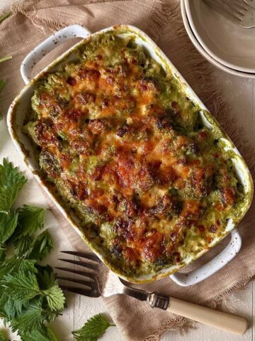 Wild garlic cauliflower cheese with nettles baked until golden in a ceramic dish.