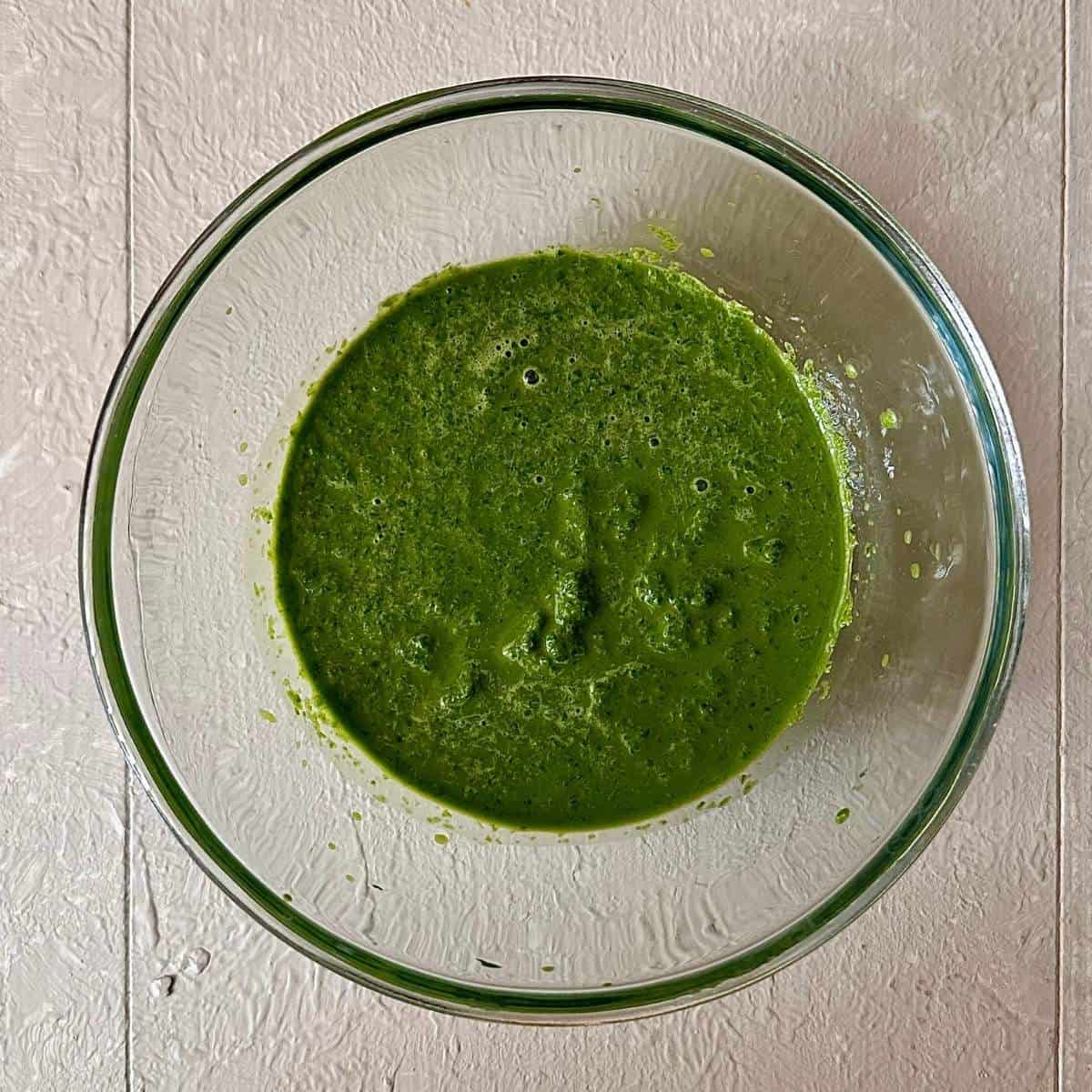 A glass bowl containing blended wild garlic.