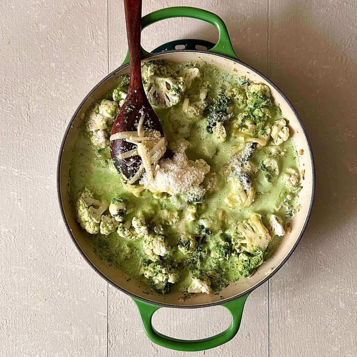 A large green casserole containing cauliflower florets in cream with nettle, pureed wild garlic and grated cheddar and parmesan.