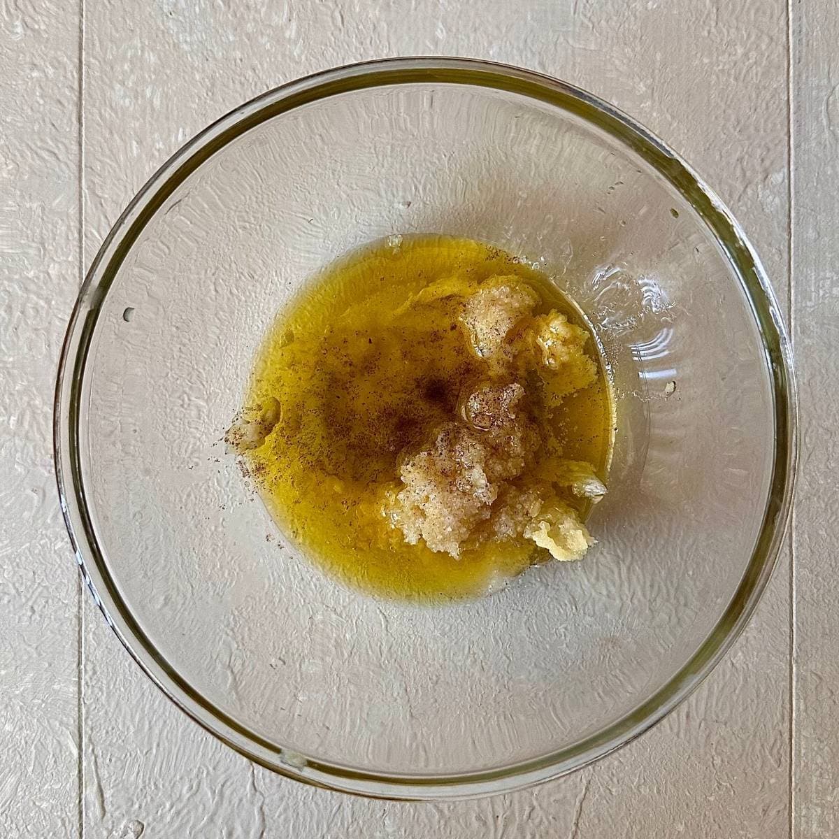 A glase bowl containing olive oil, grated garlic, and preserved lemon for the dressing for Camargue red rice, lentil and feta salad.