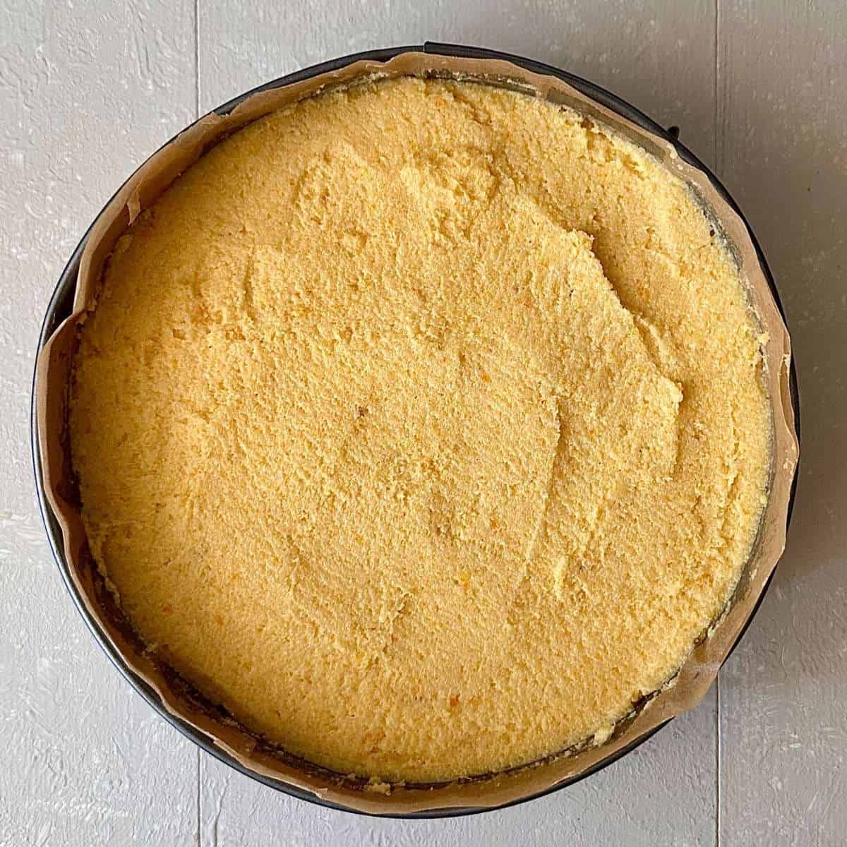 Orange polenta cake mix in a baking tin lined with parchment paper, ready to bake.