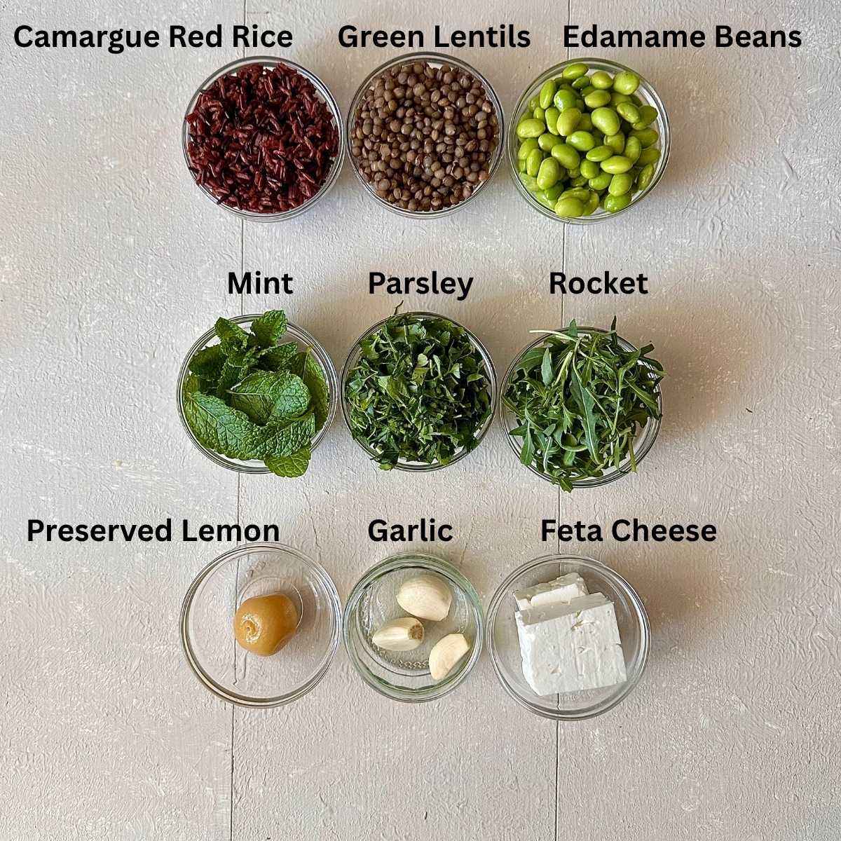 Ingredients for Camargue red rice lentil feta salad presented in small glass dishes. The ingredients are annotated.