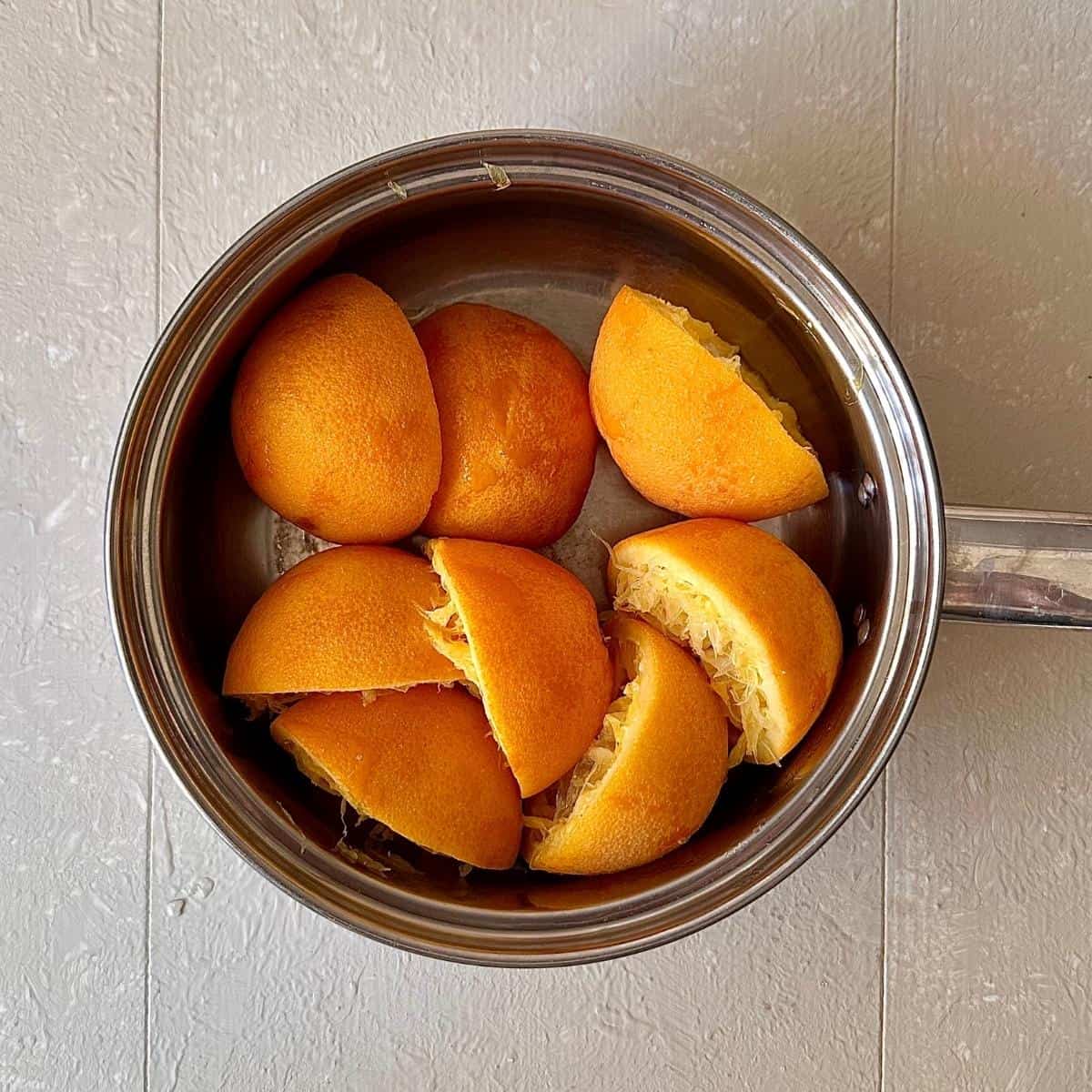 A saucepan containing orange peel boiled in water to remove bitterness for orange polenta cake.