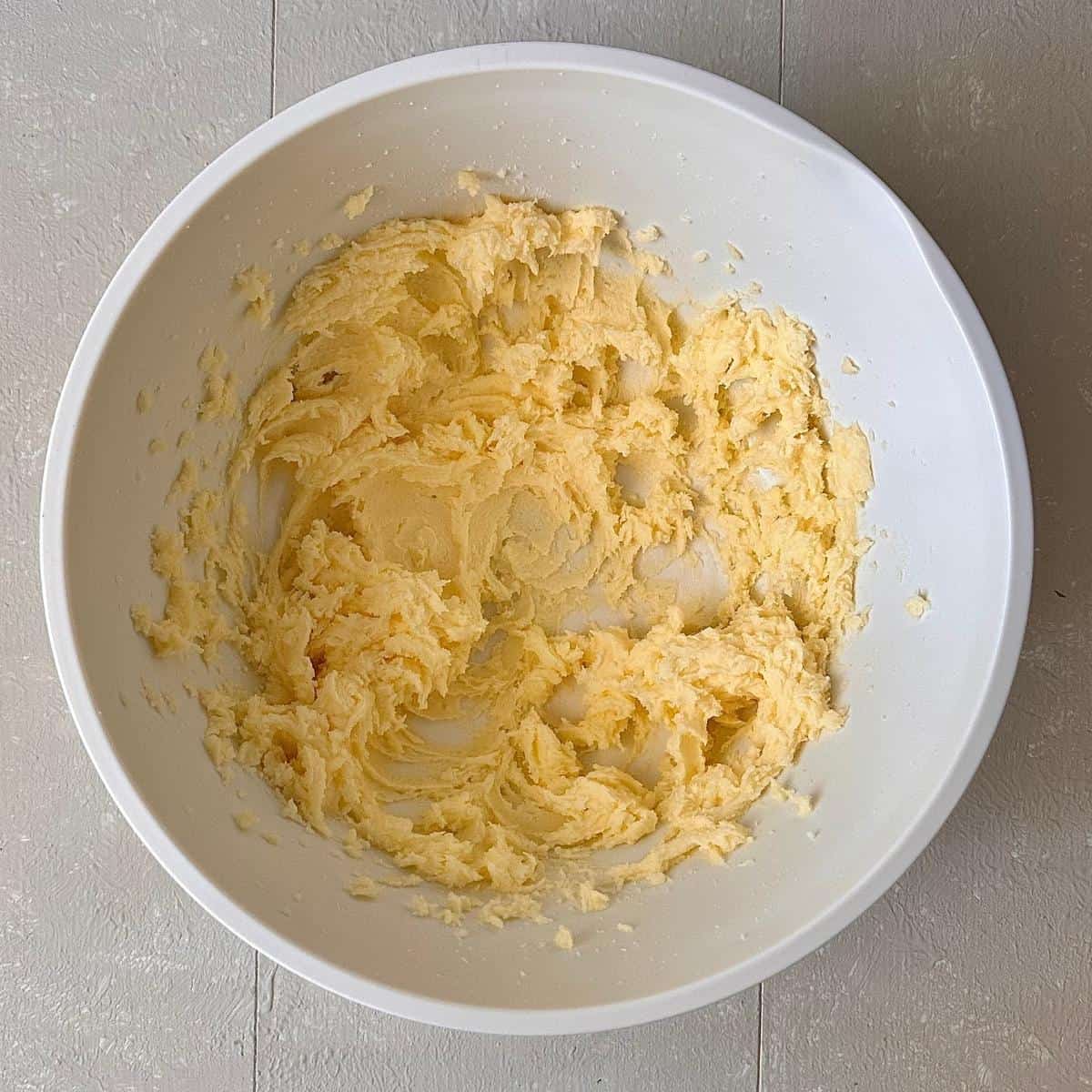 A mixing bowl containing whisked block butter and sugar for an orange polenta cake batter.