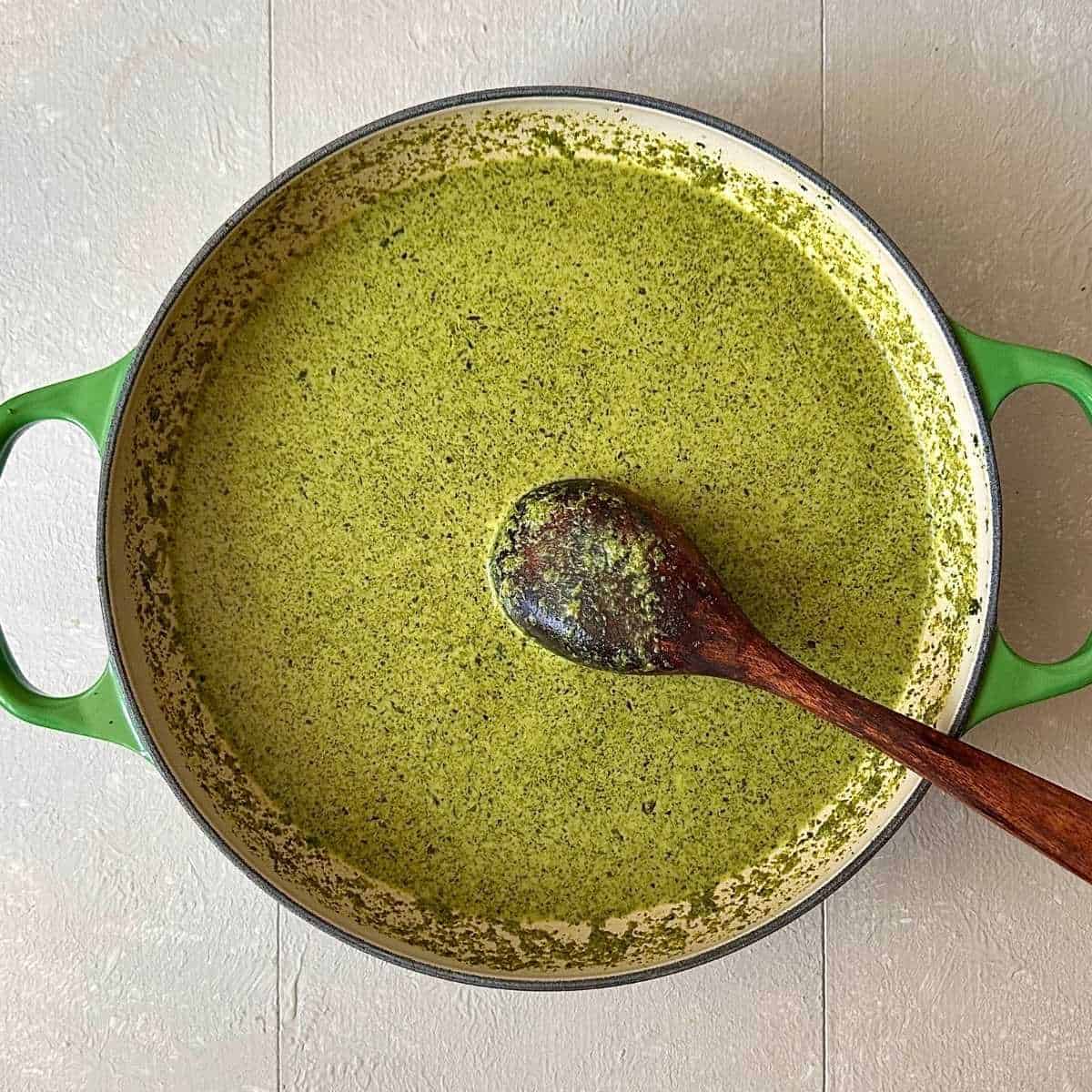 A large green casserole containing a wild greens ground paste mixed with coconut milk, for wild garlic curry.