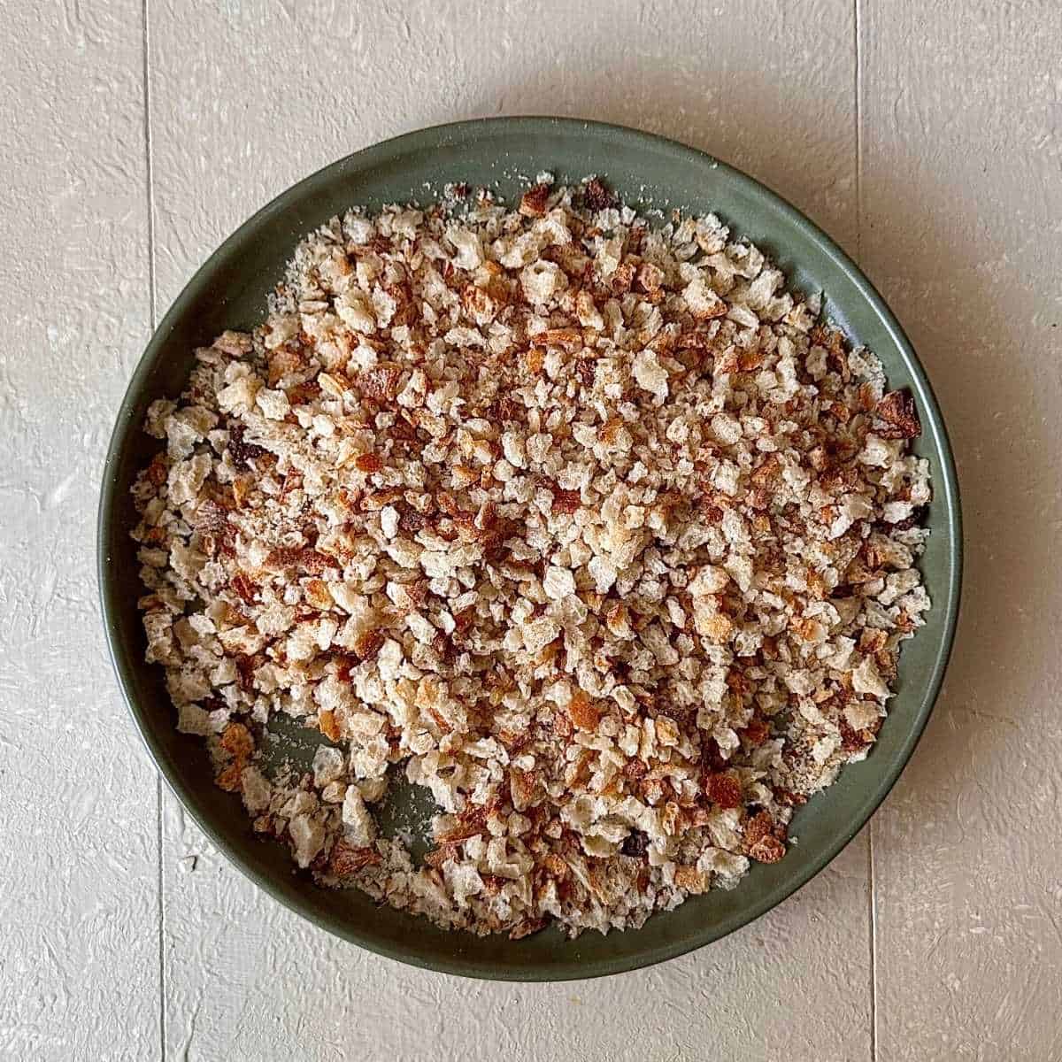 A green plate containing sourdough breadcrumbs for pangrattato crispy Italian breadcrumbs recipe.