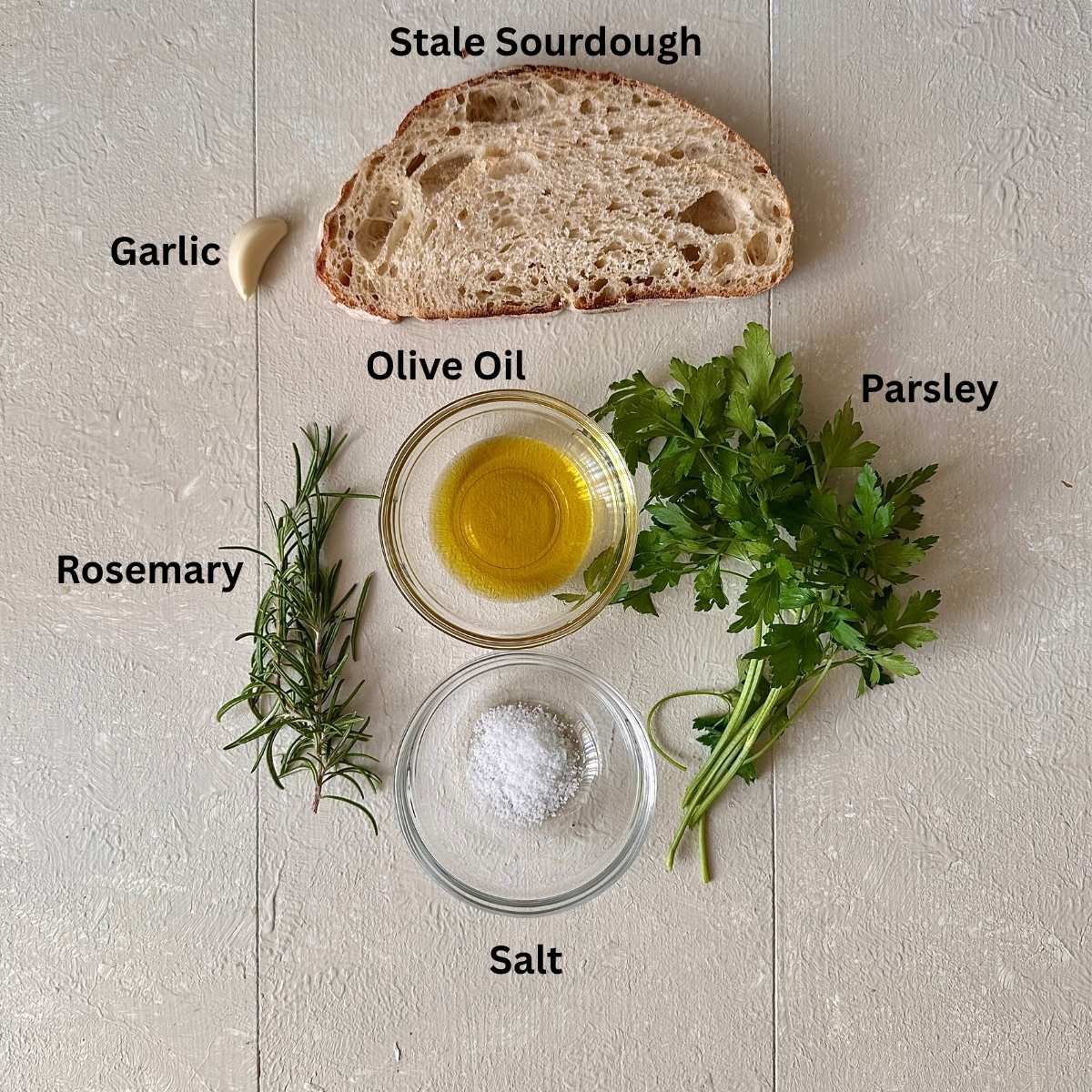Ingredients for pangrattato crispy Italian breadcrumbs recipe laid on a white background. The ingredients are annotated.