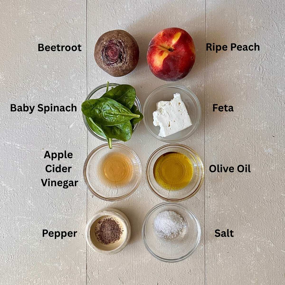 Ingredients for beetroot, peach and feta salad in small glass dishes, on a white background. The ingredients are annotated.