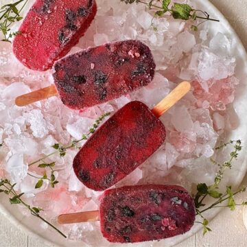 Four rose and basil seed popsicles displayed in a bowl of crushed ice.