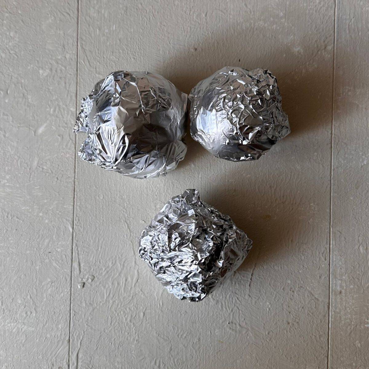 Three beetroot wrapped in tin foil ready for baking. For beetroot, peach ad feta salad.