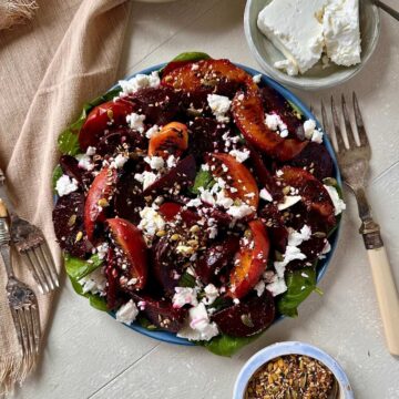 Overhead view of beetroot and peach salad with feta, baby spinach and toasted seeds.