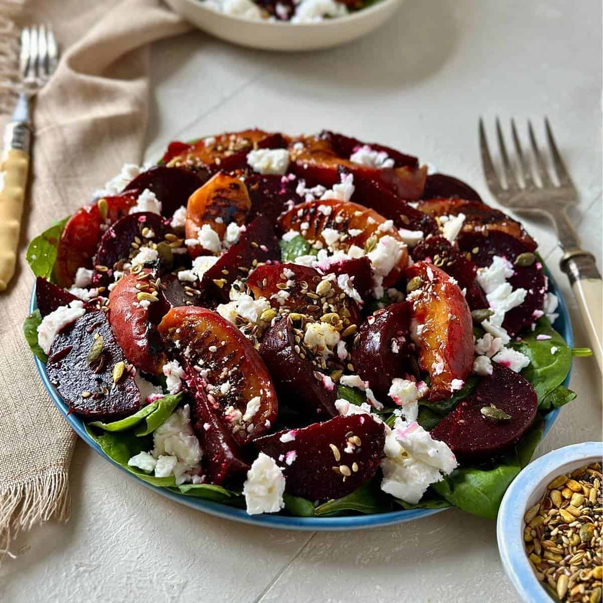 A plate of beetroot, peach and feta salad garnished with super seed mix.