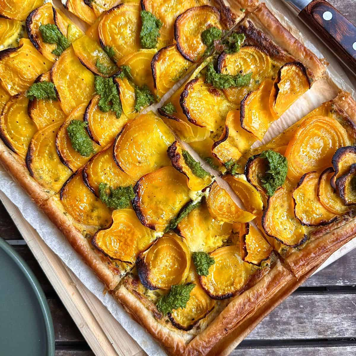 Close-up of a baked beetroot tart garnished with a beetroot leaf pesto.