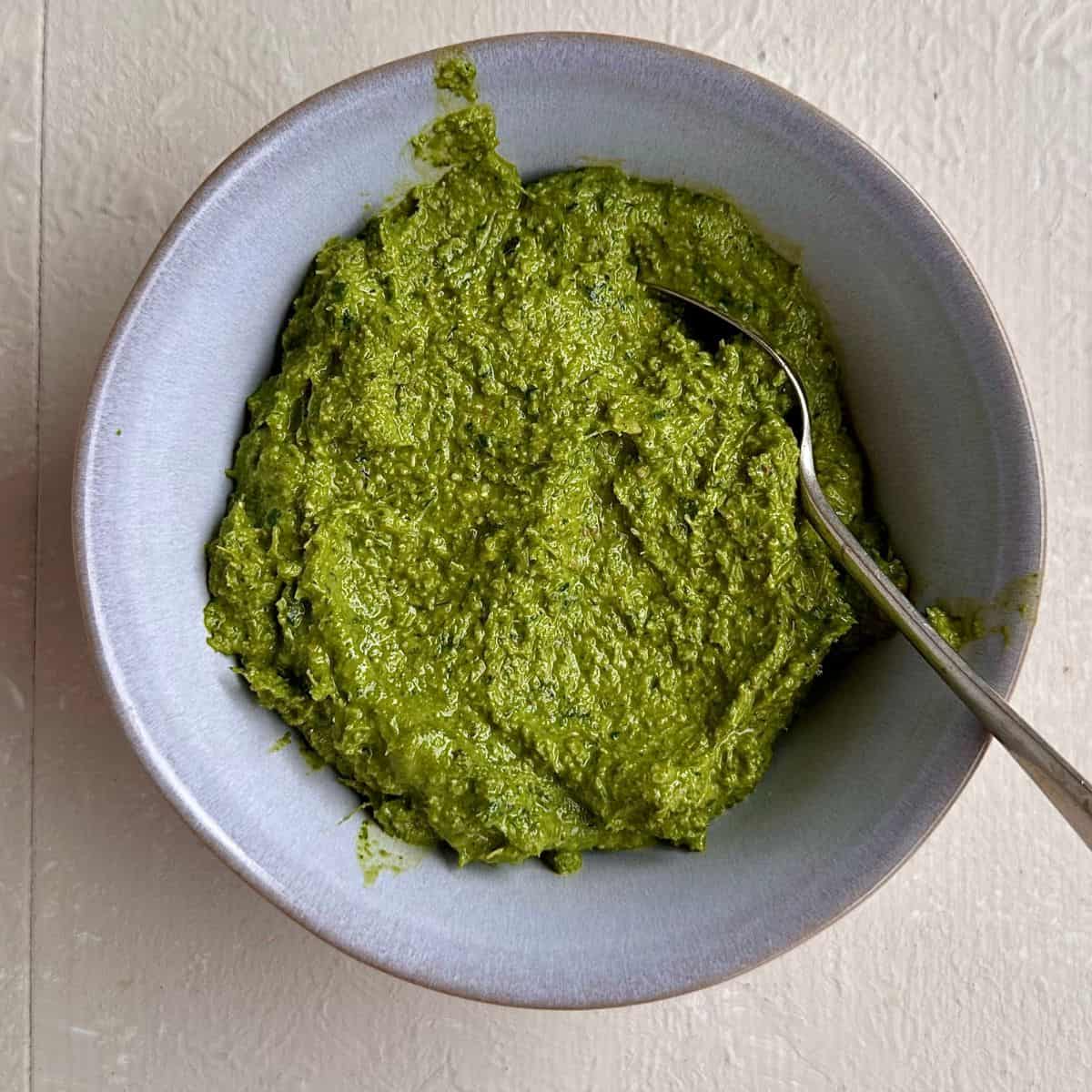 A bowl containing beetroot leaf pesto, for a beetroot tart recipe.