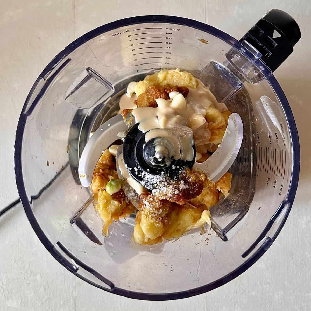 A blender jug containing baked courgette flesh, garlic, sea salt and tahini for courgette moutabbal recipe.