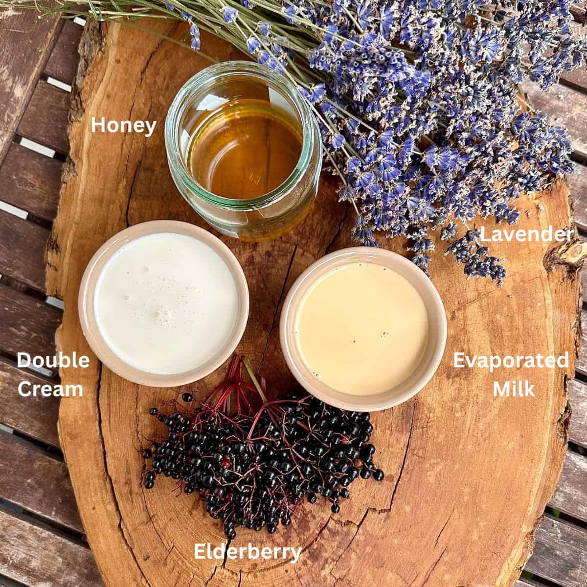 Ingredients for elderberry and lavender ice cream displayed on a rustic tree trunk slice. The ingredients are annotated.