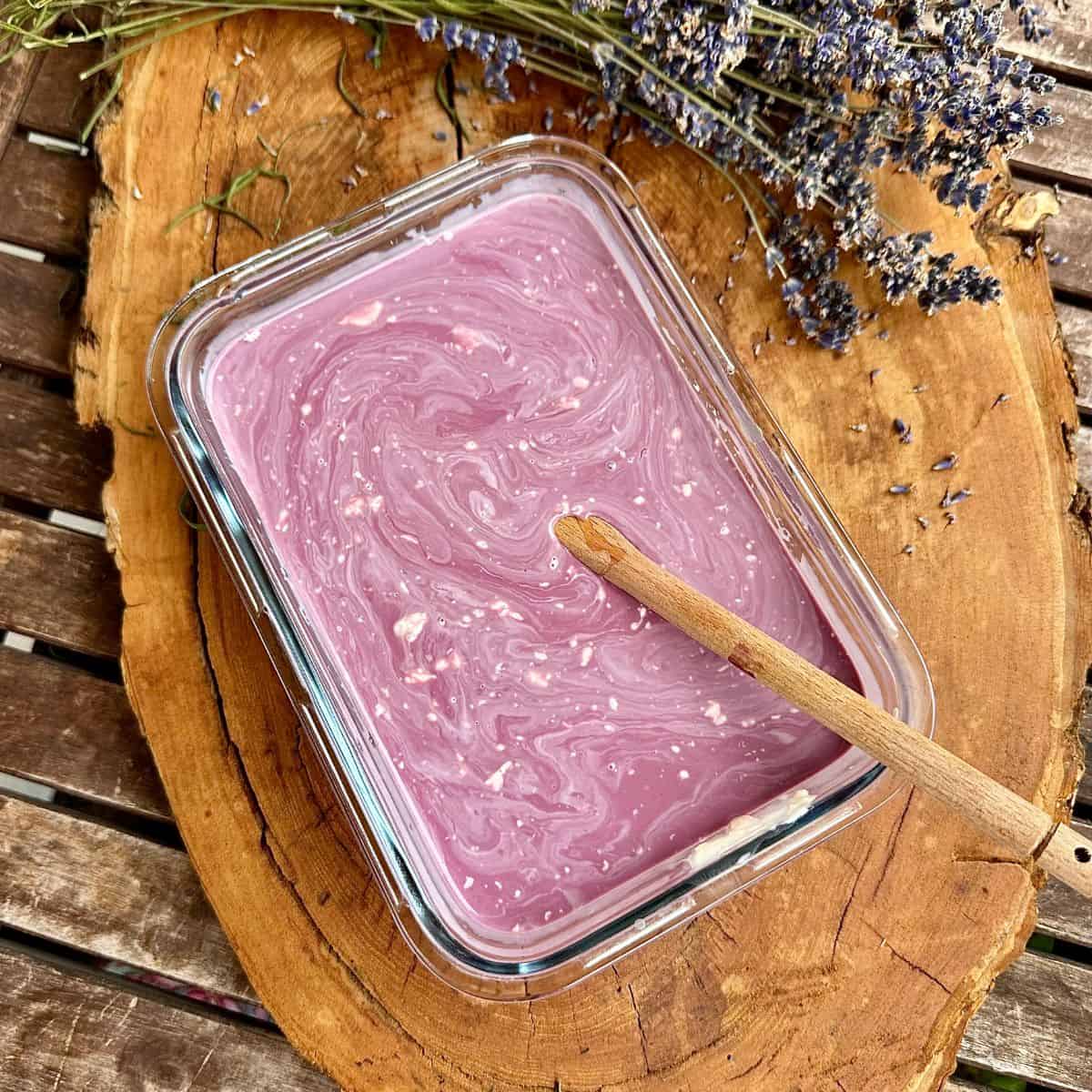 A 1.5 litre glass dish containing elderberry syrup, lavender infused evaporated Milk, double cream and honey, mixed together ready to freeze for elderberry lavender ice cream.