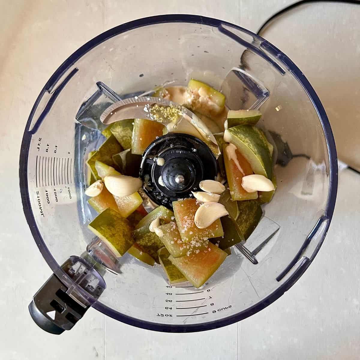 A jug blender containing watermelon rind, garlic, tahini, olive oil, lemon juice and salt, ready to blend together to make watermelon rind hummus,