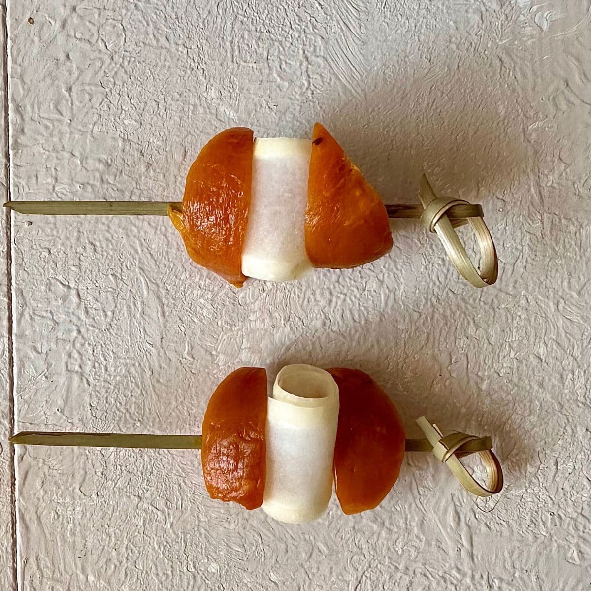 Two golden beetroot wedge and cucumber ribbon skewers for a beetroot aguachile shot.