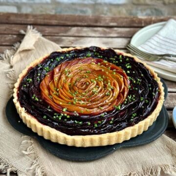 A beetroot and goat cheese tart made with golden beetroot and red beetroot. Garnished with chives.