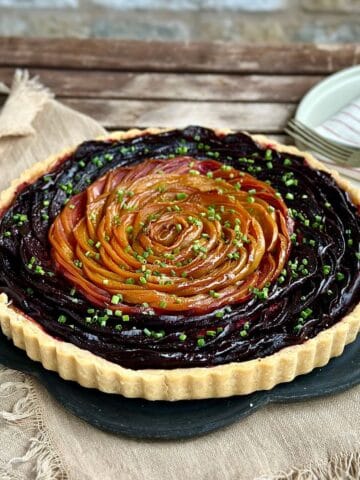 A beetroot and goat cheese tart made with golden beetroot and red beetroot. Garnished with chives.