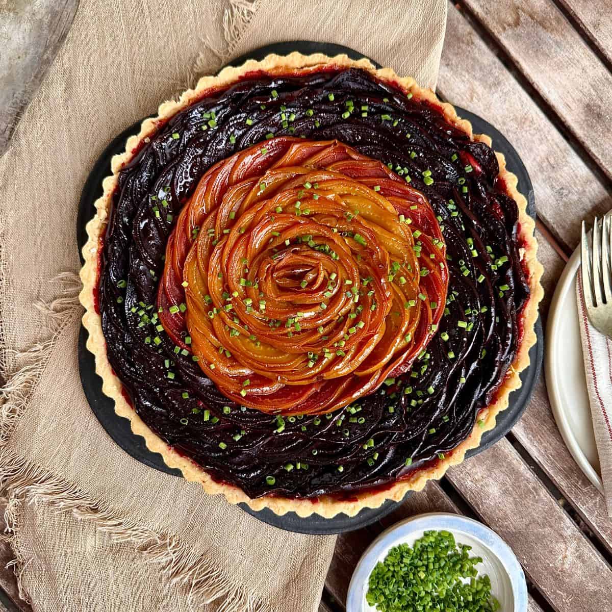 A beetroot and goats cheese tart, made with golden and red beetroot, garnished with chives.