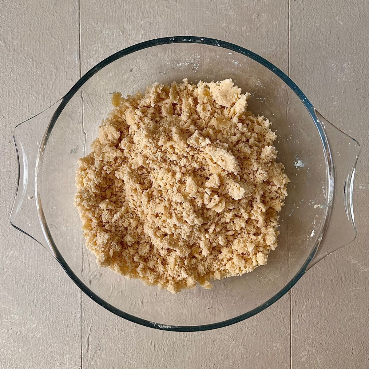A glass bowl containing flour and butter mixed together to breadcrumbs consistency for a beetroot and goats cheese tart.
